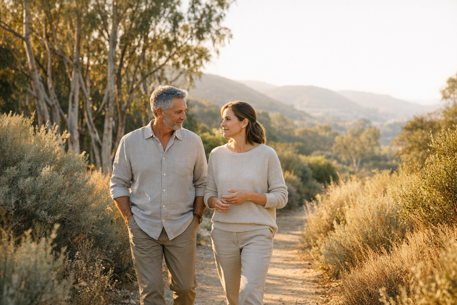 Two adults walking on a path through native California landscaping, engaged in conversation.