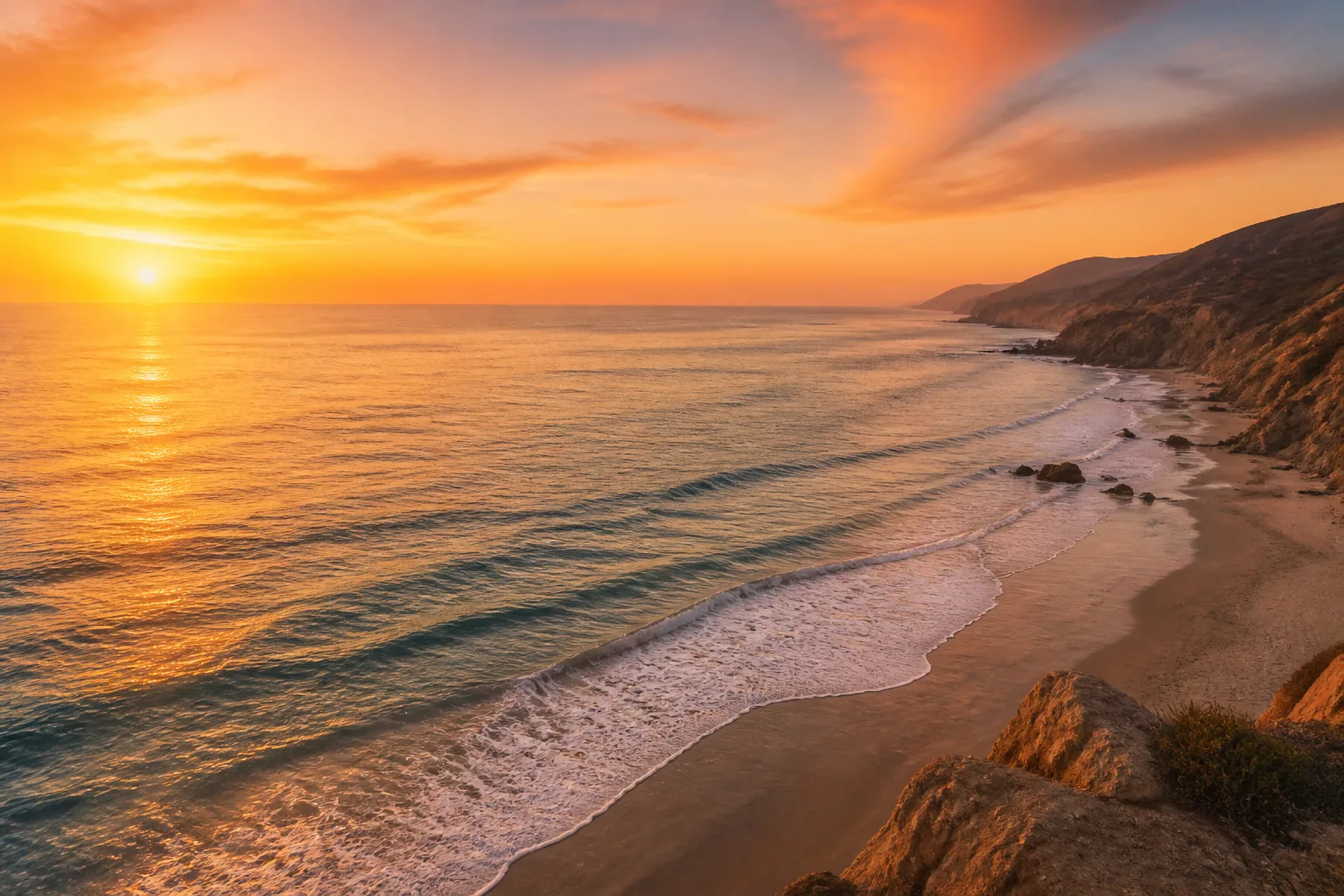 Serene view of a secluded Malibu beach at golden hour with soft waves and warm sky.